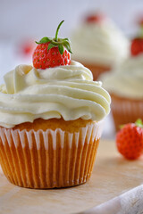 Tasty and fragrant cupcakes with strawberries and gentle cream on a white background