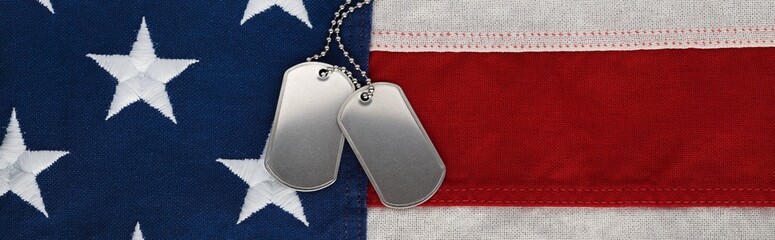 US military soldier's dog tags, rough and worn with blank space for text, on the American flag. Memorial Day or Veterans Day concept.