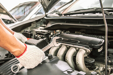 Car care maintenance and servicing, Close-up hands of auto mechanic are using the wrench to repairing car engine problems at auto repair garage. Concepts of check and services insurance.