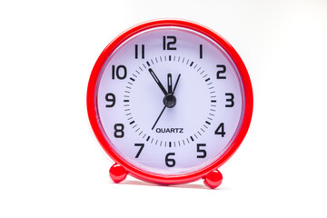 Small red alarm clock show the running time. A modern clock with red frame. Smile face of a clock. Close up on a red plastic watch with second pointer on white background. Five to twelve 
