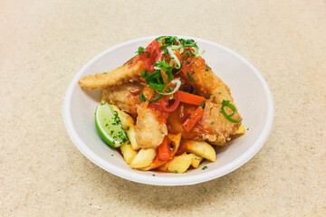 Takeaway fish and chips with sweet and sour sauce and a wedge of green lime
