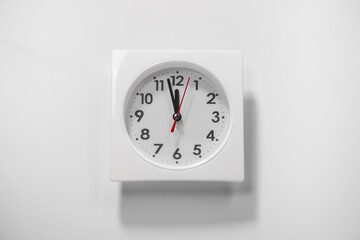 It is five to twelve, the clock is ticking. white Watch shows the time 5 before 12. Close up to a wall Clock, with five minutes to twelve o'clock. Time is running out. White background with copy space