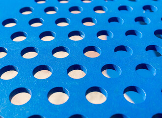 Closeup shot of a blue perforated metal sheet under sunlight