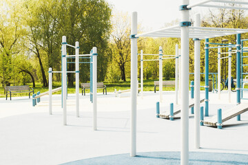 Fototapeta premium Outdoor sports ground. Pull up bars, crossbars, equipment and rubber flooring for training in the park. Summer sunny day. No people