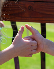 Two children playing a thumb war battle with the objective to pin the opposing player's thumb