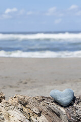 Fototapeta na wymiar Heart rock found on beach with ocean background for greeting card