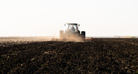 Fototapeta premium Tractor is preparing the land at dusk