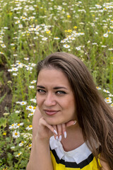 Fototapeta premium Portrait of a young beautiful girl in a field with flowers, girl smiling, happy