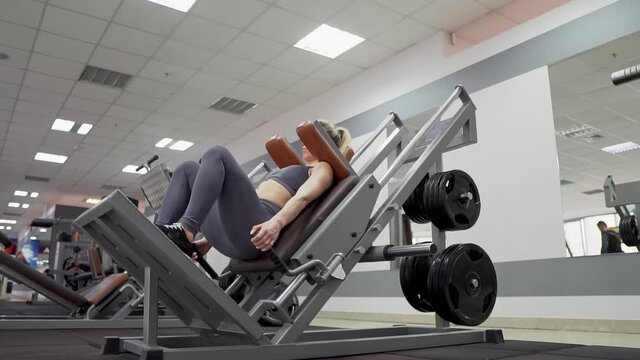 Fit woman practicing back squats in exercise machine