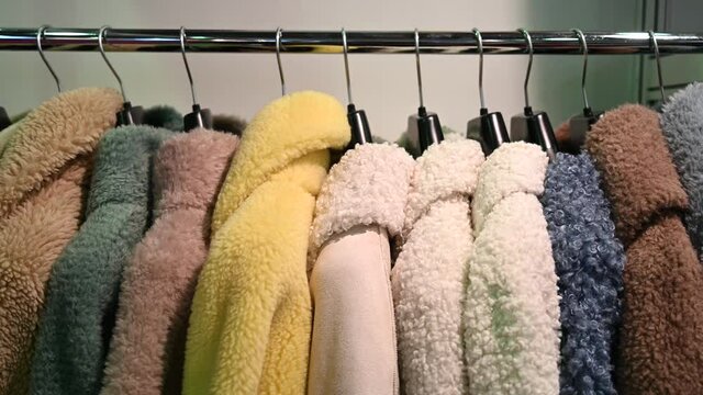Faux fur coats. Women's winter fur coats hang in a row on hangers
