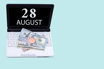 Fototapeta na wymiar Laptop with the date of 28 august and cryptocurrency Bitcoin, dollars on a blue background. Buy or sell cryptocurrency. Stock market concept.