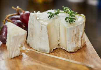 Fototapeta na wymiar Selected French cheeses with grapes, on wooden board with rosemary and knife