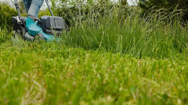 lawn service. Lawn mowing. A man mows a lawn with a lawn mower in a garden.cutting green grass in backyard, garden service