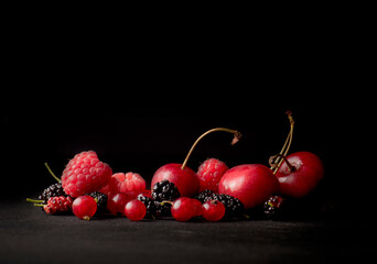 raspberries and mulberries, cherries and berries on a dark background, copy space
