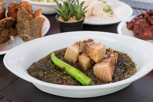 Delicious laing with fried pork belly bits with other Filipino cuisine. Sumptuous lunch or buffet at an al fresco restaurant.
