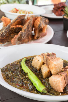 Delicious laing with fried pork belly bits with other Filipino cuisine. Sumptuous lunch or buffet at an al fresco restaurant.