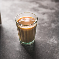 Indian chai in glass cups with metal kettle and other masalas to make the tea.