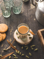 Indian chai in glass cups with metal kettle and other masalas to make the tea.