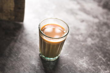 Indian chai in glass cups with metal kettle and other masalas to make the tea.