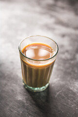 Indian chai in glass cups with metal kettle and other masalas to make the tea.