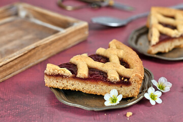 Single slice of pie called 'Linzer Torte', a traditional Austrian shortcake pastry topped with fruit preserves and nuts with lattice design