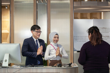 young Asian reception team hotel front desk welcoming . Asian reception welcoming the customer into hotel front desk counter for service the customer,