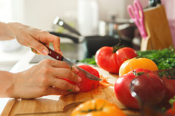Woman is slicing red tomatoes on wooden chopping board