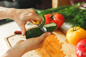 Female hand with peeler and cucumber