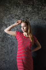 The girl the blonde in a red striped dress with glasses on a dark background.