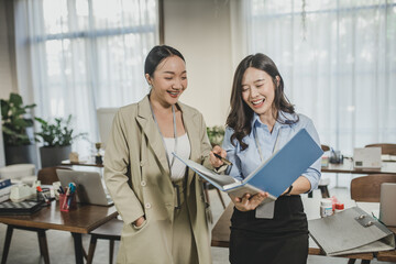 young Asian woman reading a document standing at office desk. business woman reading document on office. businesswoman sitting at workplace and reading document in office