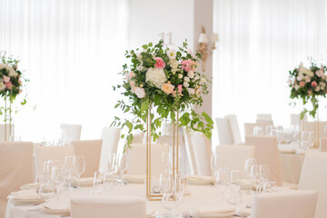 Centerpiece made of green leaves and fresh flowers stands on the dinner table. Wedding day. Fresh flowers decorations.