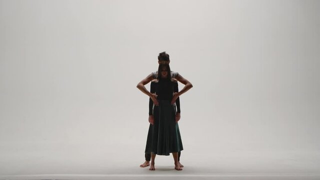 Elements of modern choreography, contemporary performed by a young couple of dancers on a white studio background. Man and woman dance passionately, expressing their feelings in a dance. Slow motion.