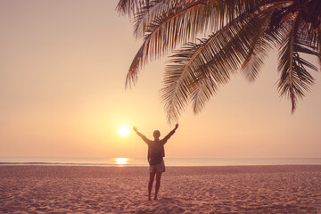 Copy space of woman rise hand up on sunset sky at beach and palm tree background.