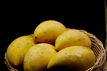 ripe mangoes in a wicker basket isolated on black
