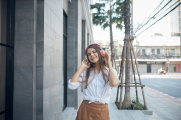 Young woman listening to music via headphones on the street. woman smiling happy using smartphone and headphones