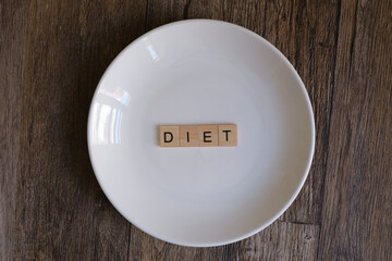 Wooden blocks with DIET word on a empty white plate on a wooden table