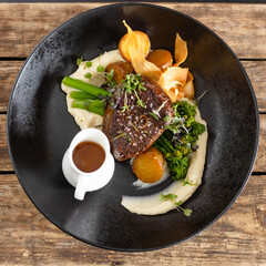 Steak dishes with potatoes and sauce on a wood background