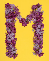 The letter M is lined with lilac flowers on a yellow background. For lettering, composing words.