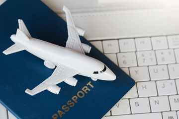 Model white airplane, white laptop and passport . Buying online ticket booking for travel concept