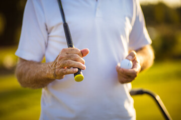 Senior golfer on court holding ball.