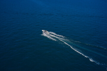 Naklejka na ściany i meble Top view of a white boat sailing in the blue sea. Aerial view luxury motor boat. A boat with a motor on blue water. Top view of the boat.