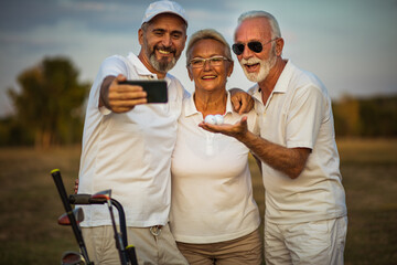 Senior golfers using phone and taking self portrait.