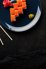 rolls in caviar on a blue plate on a black textured background