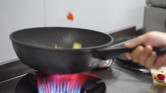 Hands of cook frying vegetables on pan