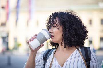  Woman on street and drinking coffee. Looking at camera. © liderina