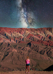 hiker girl in the desert with a mountain in front and the milky way on top