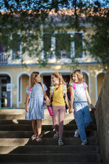 Three little school girls leaving school together.