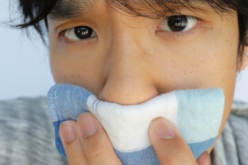日本人男性がハンカチで口と鼻を押さえている