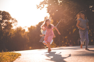 Three smiling little girls running trough nature.