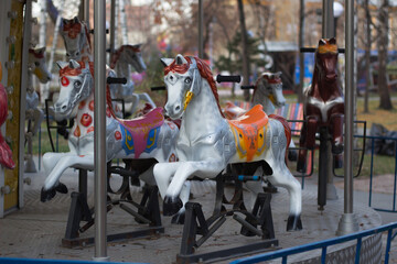 Empty children's entertainment carousel. Running horses carousel. City park. Focus on the Central horse.